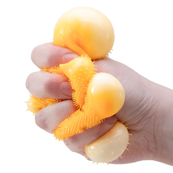 Hånd der klemmer en orange NeeDoh Fuzz Ball Wild Cats squishy
