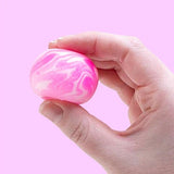 NeeDoh Teenie Swirl squishy i hvid og pink klemt i en hånd